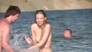 Nudist old woman caressed by the sea on the beach