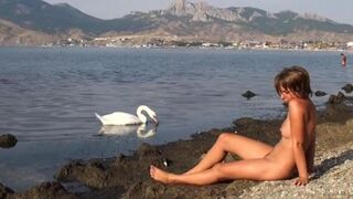 Nude beauty walks along the riverbank and admires her body