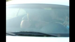 A blonde is having fun on the car hood with a guy in the street