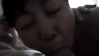 The Chinese woman practices her blowjob skills on her man in a steamy bedroom session