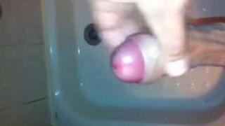 The kid caresses his dick under the shower head and plays with his cum