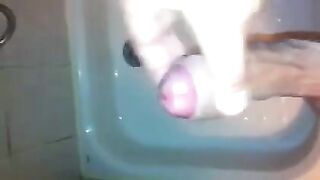 The kid caresses his dick under the shower head and plays with his cum