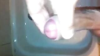The kid caresses his dick under the shower head and plays with his cum