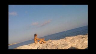 A hot girl is basking in the sun on the beach completely naked