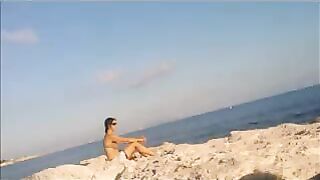 A hot girl is basking in the sun on the beach completely naked
