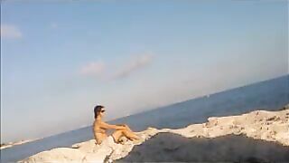 A hot girl is basking in the sun on the beach completely naked